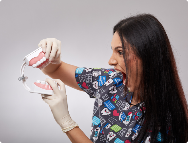 Dr Luisa holding a dental model with gloves and a playful expression